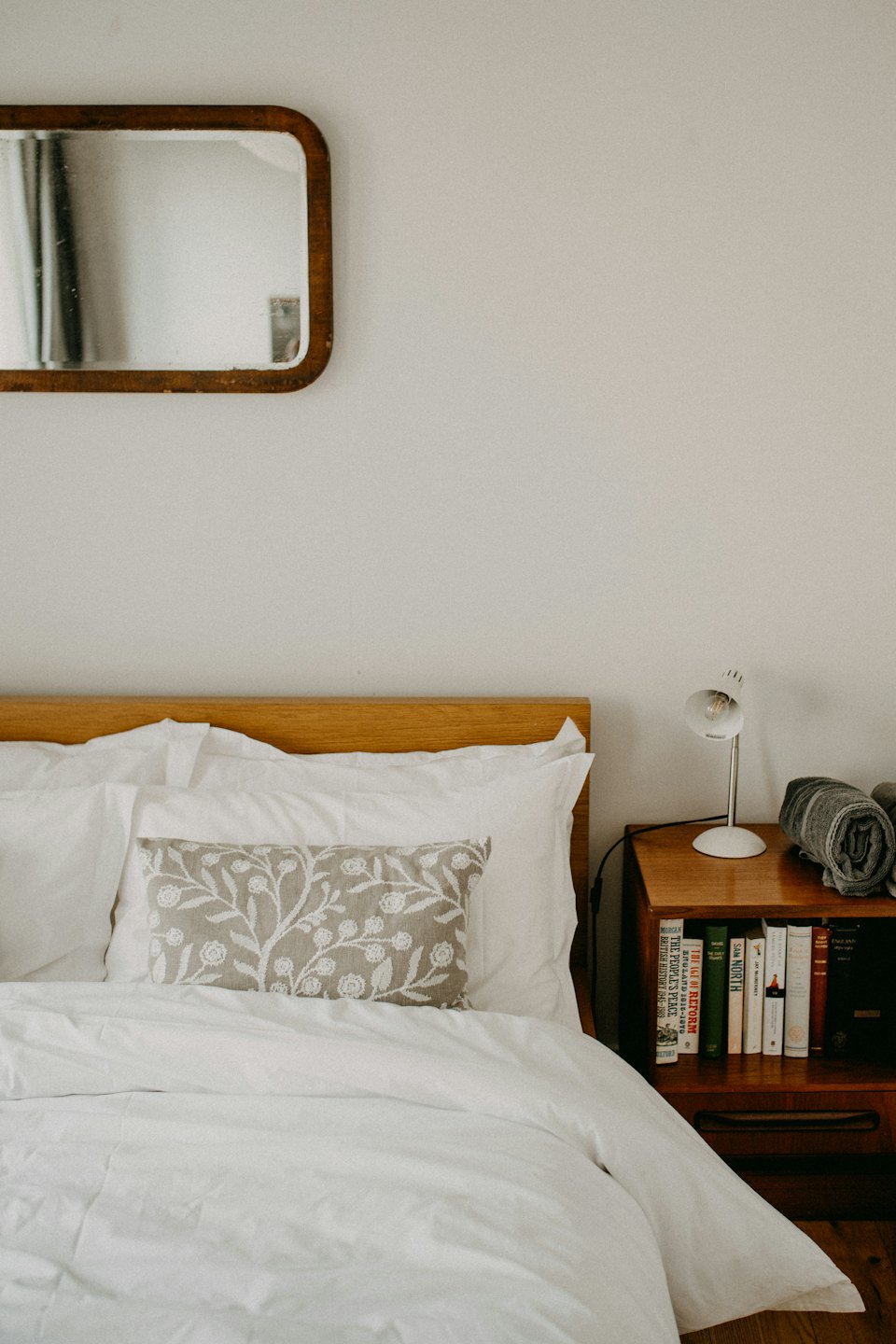Chambre minimaliste et douillette avec un lit bien fait et des touches de bois.
