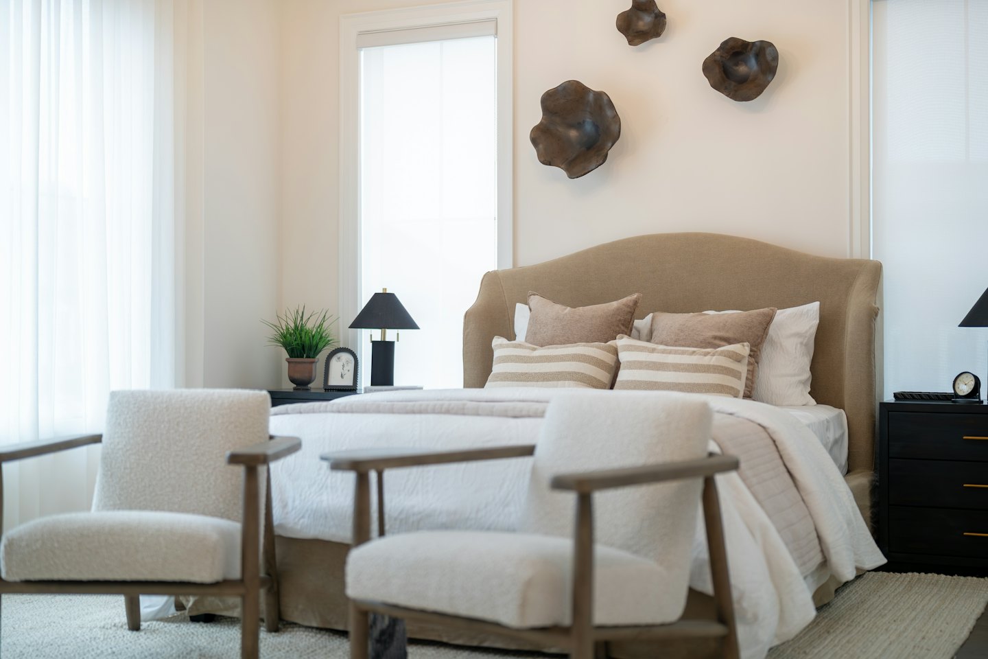 Chambre moderne avec un lit et deux fauteuils.