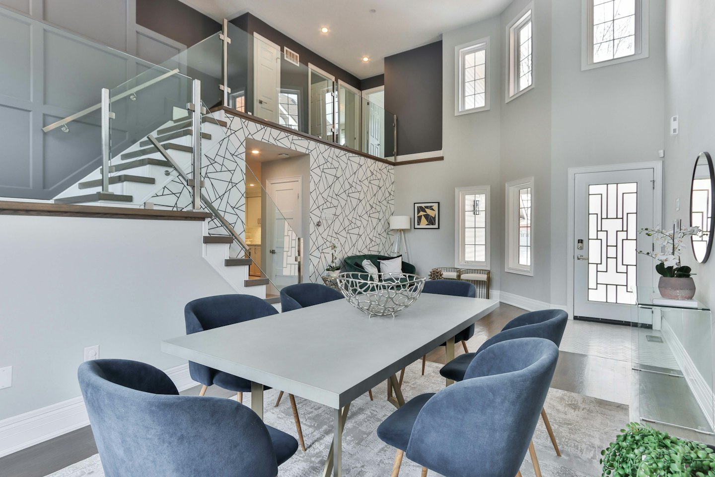 Salle à manger moderne avec chaises en velours bleu et garde-corps en verre.