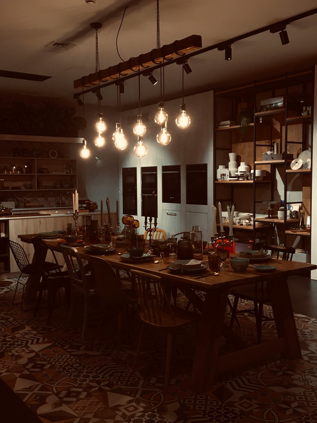 Une table de salle à manger en bois sombre ornée de candélabres et d'ampoules allumées.