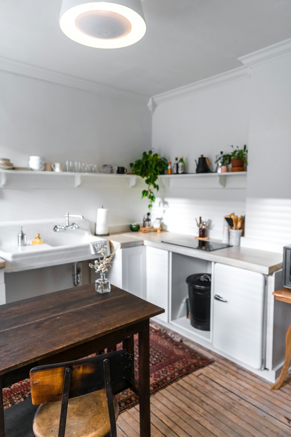 Cuisine moderne avec étagères blanches et table en bois.