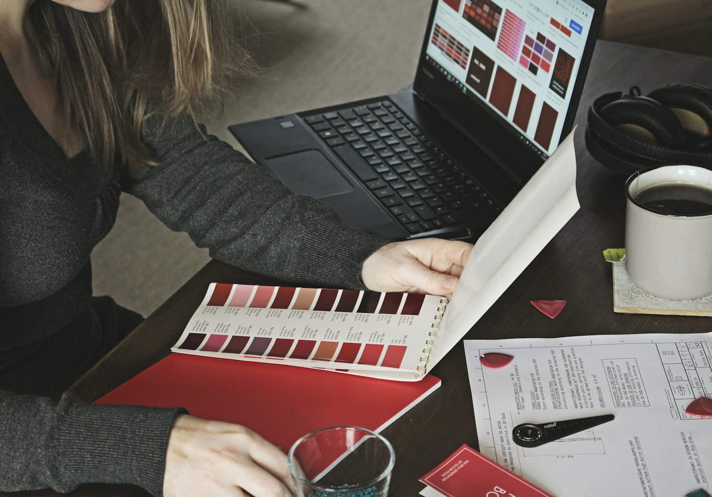 Une designer examine des échantillons de couleurs sur un ordinateur portable et dans un livre.